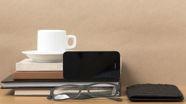 coffee,phone,eyeglasses,stack of book and wallet on wood table background