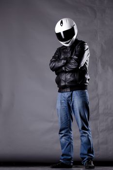 motorist with a helmet, leather jacket and jeans, on grunge background with harsh lighting