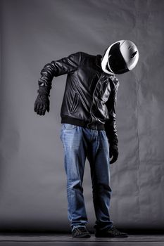 motorist with a helmet, leather jacket and jeans, on grunge background with harsh lighting