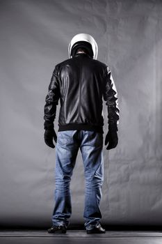 motorist with a helmet, leather jacket and jeans, on grunge background with harsh lighting