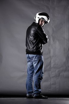 motorist with a helmet, leather jacket and jeans, on grunge background with harsh lighting