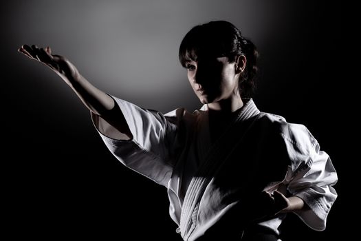 girl exercising karate, against black background