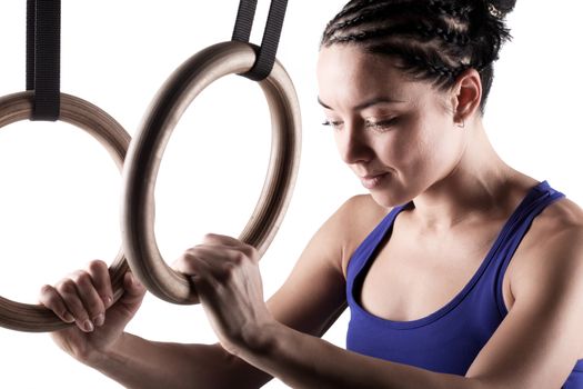 fit girl girl exercising on gymnast rings, against white background