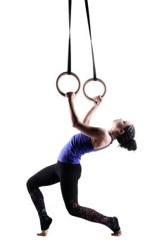 fit girl girl exercising on gymnast rings, against white background