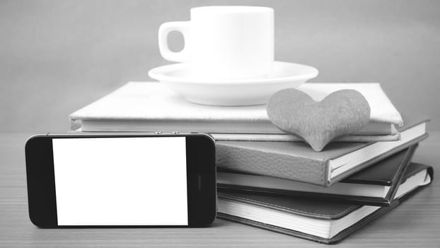 coffee,phone,stack of book and heart on wood table background black and white color