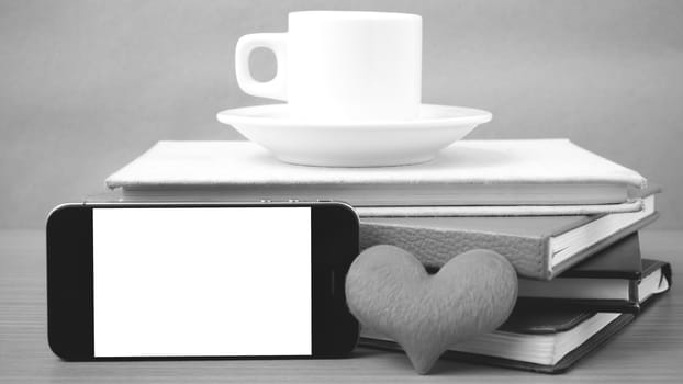 coffee,phone,stack of book and heart on wood table background black and white color