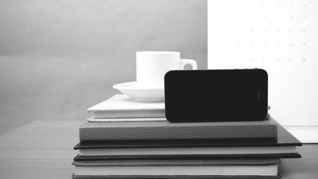 coffee,phone,stack of book and calendar on wood table background black and white color