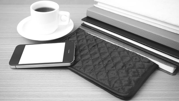 coffee,phone,stack of book and wallet on wood table background black and white color