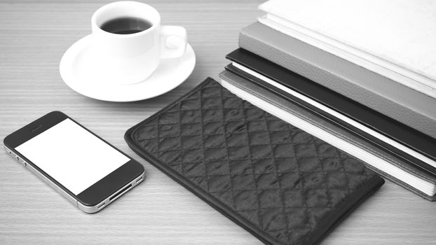 coffee,phone,stack of book and wallet on wood table background black and white color