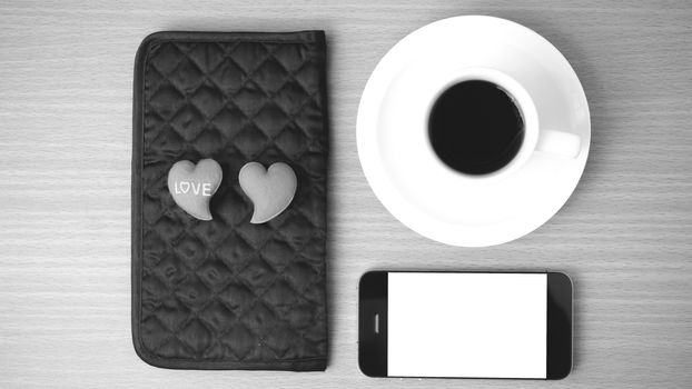 coffee,phone,wallet and heart on wood table background black and white color