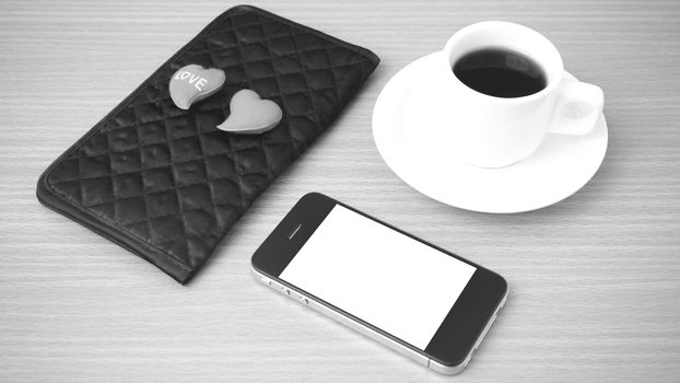 coffee,phone,wallet and heart on wood table background black and white color