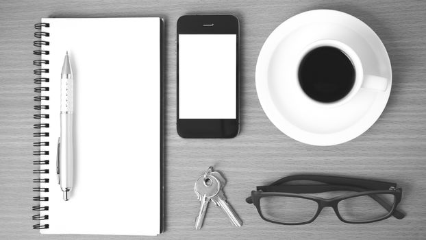 coffee,phone,notepad,eyeglasses and key on wood table background black and white color