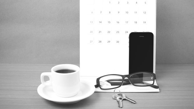 coffee,phone,eyeglasses,calendar and key on wood table background black and white color