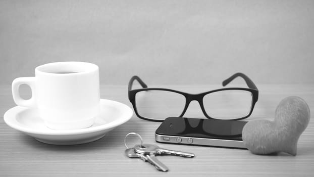 coffee,phone,eyeglasses and key on wood table background black and white color