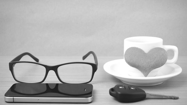 coffee,phone,eyeglasses and car key on wood table background black and white color