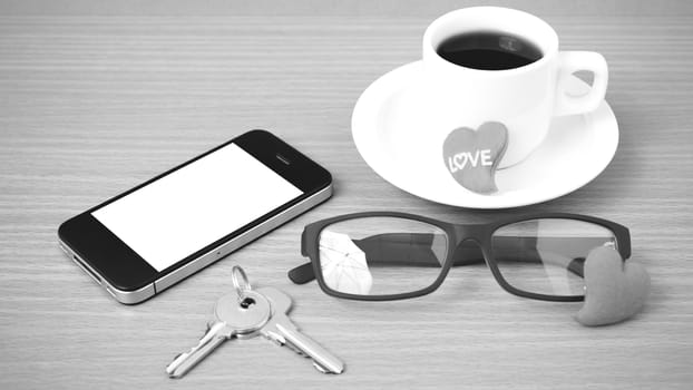 coffee,phone,eyeglasses and key on wood table background black and white color