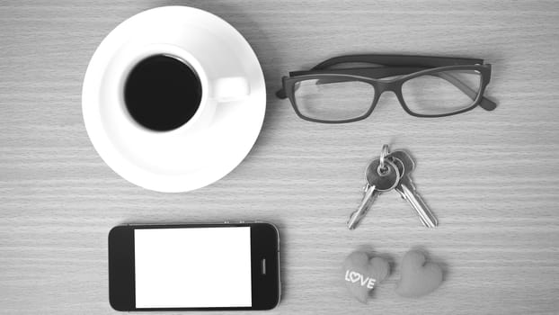 coffee,phone,eyeglasses and key on wood table background black and white color