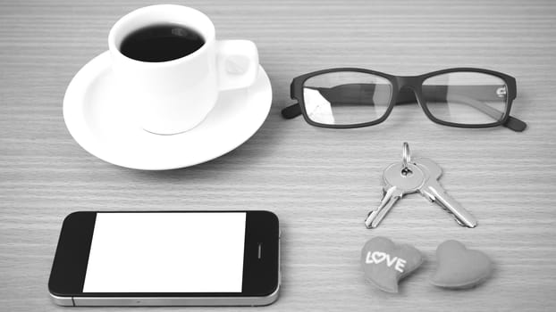 coffee,phone,eyeglasses and key on wood table background black and white color