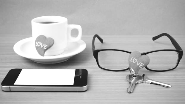 coffee,phone,eyeglasses and key on wood table background black and white color