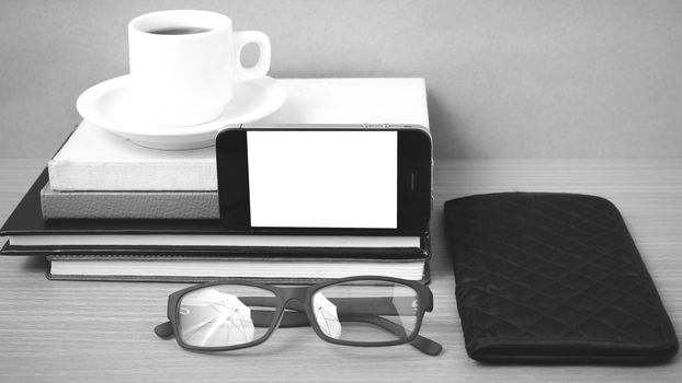 coffee,phone,eyeglasses,stack of book and wallet on wood table background black and white color