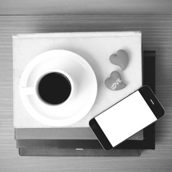 coffee,phone,stack of book and heart on wood table background black and white color