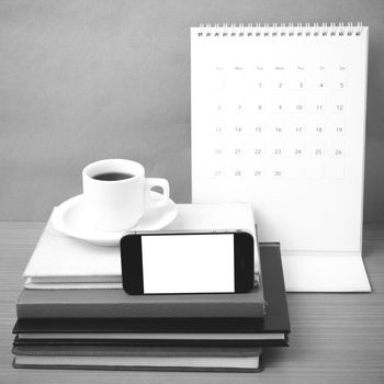 coffee,phone,stack of book and calendar on wood table background black and white color