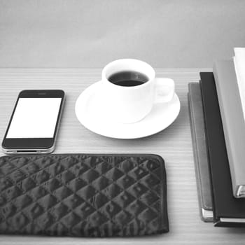 coffee,phone,stack of book and wallet on wood table background black and white color