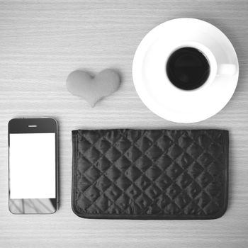 coffee,phone,wallet and heart on wood table background black and white color