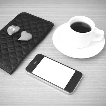 coffee,phone,wallet and heart on wood table background black and white color