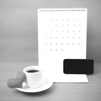 coffee,phone,calendar and heart on wood table background black and white color