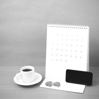 coffee,phone,calendar and heart on wood table background black and white color