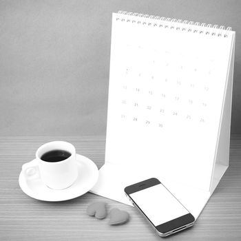 coffee,phone,calendar and heart on wood table background black and white color