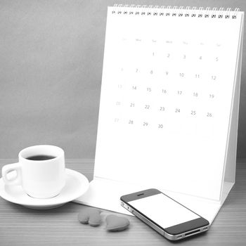 coffee,phone,calendar and heart on wood table background black and white color