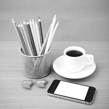 coffee,phone,color pencil and heart on wood table background black and white color