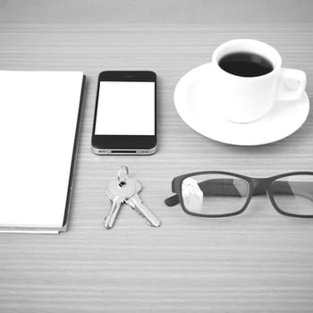 coffee,phone,notepad,eyeglasses and key on wood table background black and white color