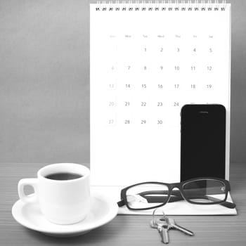 coffee,phone,eyeglasses,calendar and key on wood table background black and white color