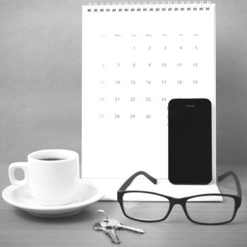 coffee,phone,eyeglasses,calendar and key on wood table background black and white color