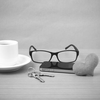 coffee,phone,eyeglasses and key on wood table background black and white color