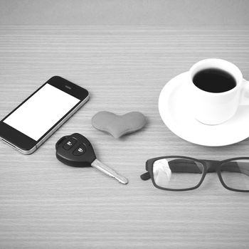 coffee,phone,eyeglasses and car key on wood table background black and white color