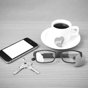 coffee,phone,eyeglasses and key on wood table background black and white color