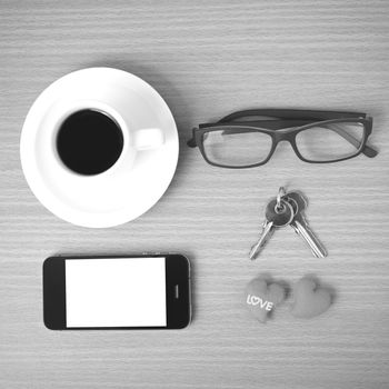 coffee,phone,eyeglasses and key on wood table background black and white color