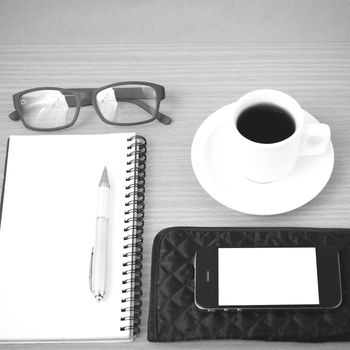 coffee,phone,eyeglasses,notepad and wallet on wood table background black and white color