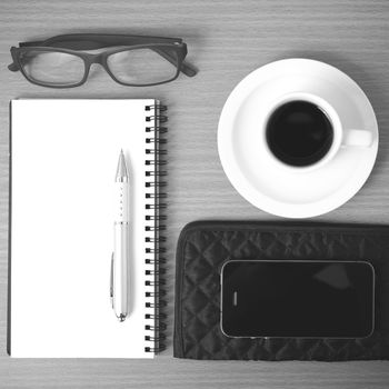 coffee,phone,eyeglasses,notepad and wallet on wood table background black and white color