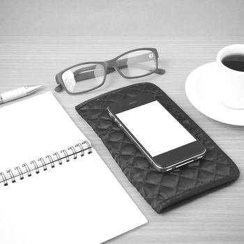 coffee,phone,eyeglasses,notepad and wallet on wood table background black and white color