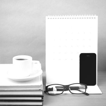 coffee,phone,eyeglasses,stack of book and calendar on wood table background black and white color