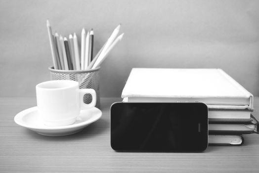 coffee,phone,stack of book and color pencil on wood table background black and white color