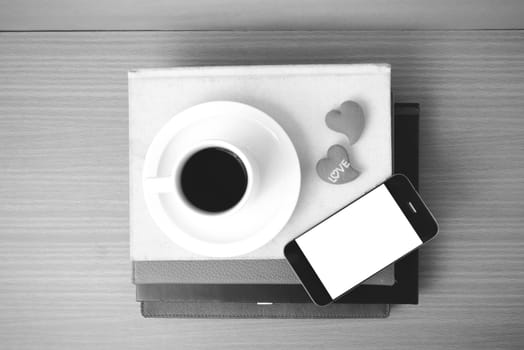 coffee,phone,stack of book and heart on wood table background black and white color