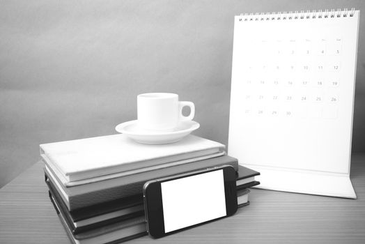 coffee,phone,stack of book and calendar on wood table background black and white color