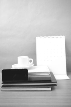 coffee,phone,stack of book and calendar on wood table background black and white color