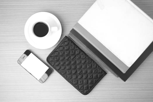 coffee,phone,stack of book and wallet on wood table background black and white color